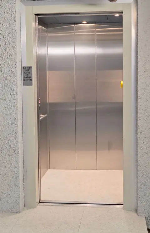 Stainless steel commercial lift cabin with doors open, installed by Lift Ease