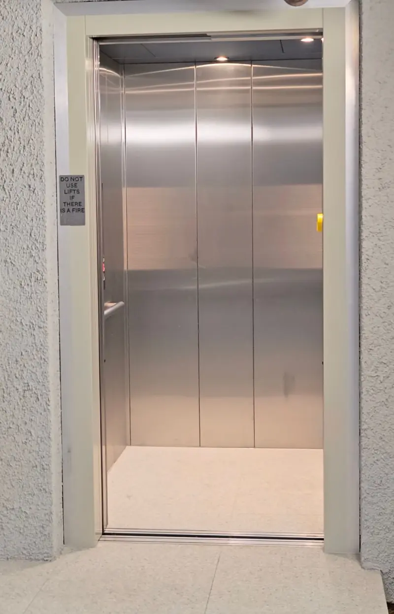 Stainless steel commercial lift cabin with doors open, installed by Lift Ease