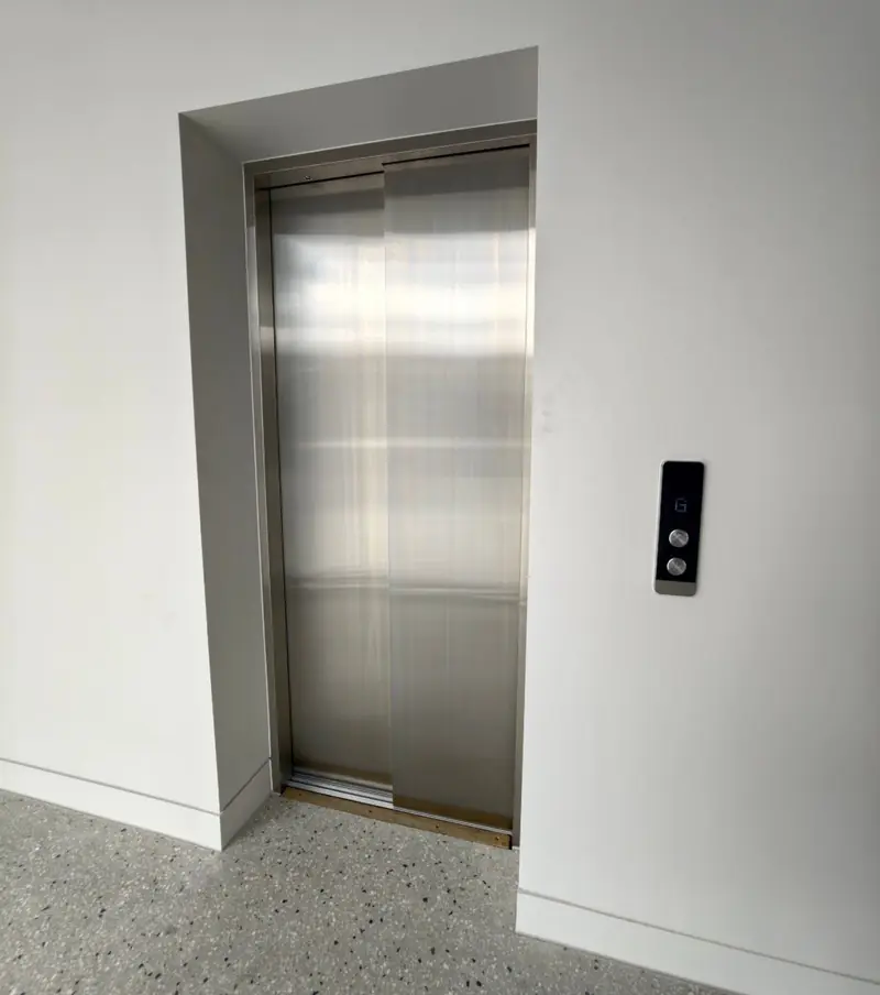 Stainless steel commercial lift doors with a landing call panel, installed by Lift Ease