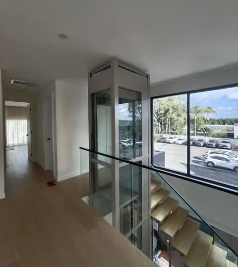 Glass lift shaft beside a staircase in a modern home, installed by Lift Ease