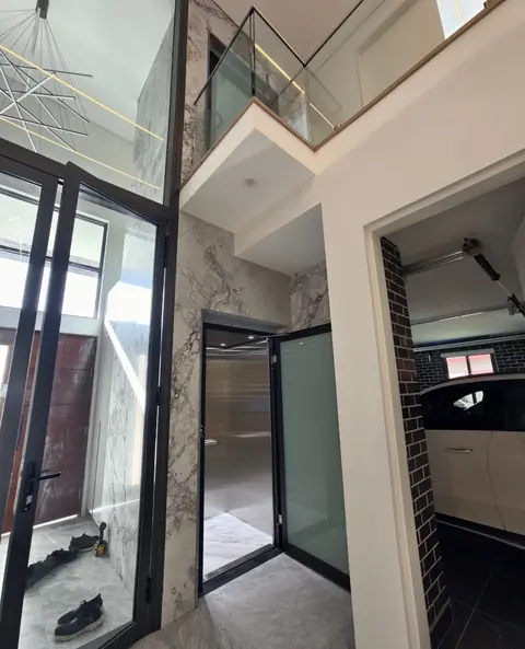 Black-framed glass lift entry in a marble home interior, installed by Lift Ease
