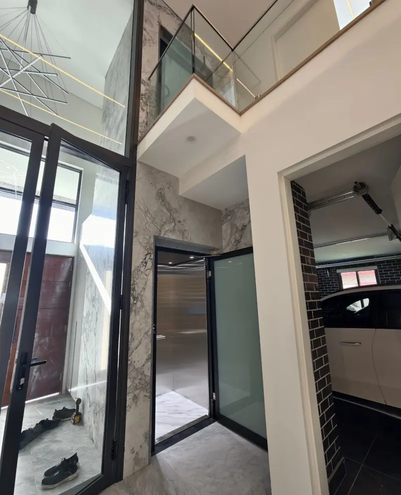 Black-framed glass lift entry in a marble home interior, installed by Lift Ease