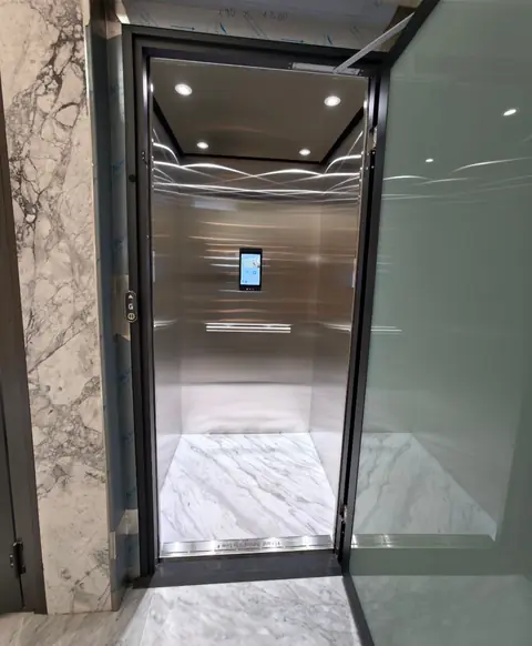 Stainless steel lift cabin with a touchscreen and marble floor, installed by Lift Ease