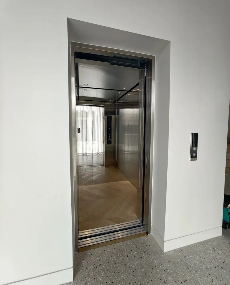 Stainless steel lift with doors open onto a herringbone timber floor, installed by Lift Ease