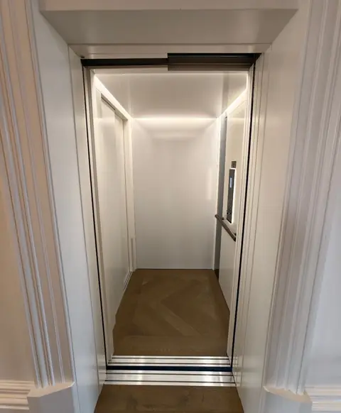 Bright white lift cabin with a herringbone timber floor, installed by Lift Ease
