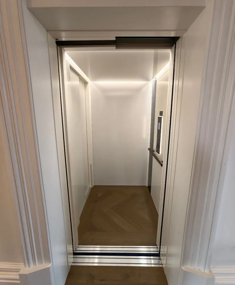 Bright white lift cabin with a herringbone timber floor, installed by Lift Ease