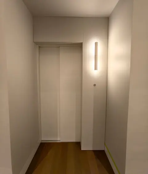 White lift doors with a wall light in a home hallway, installed by Lift Ease