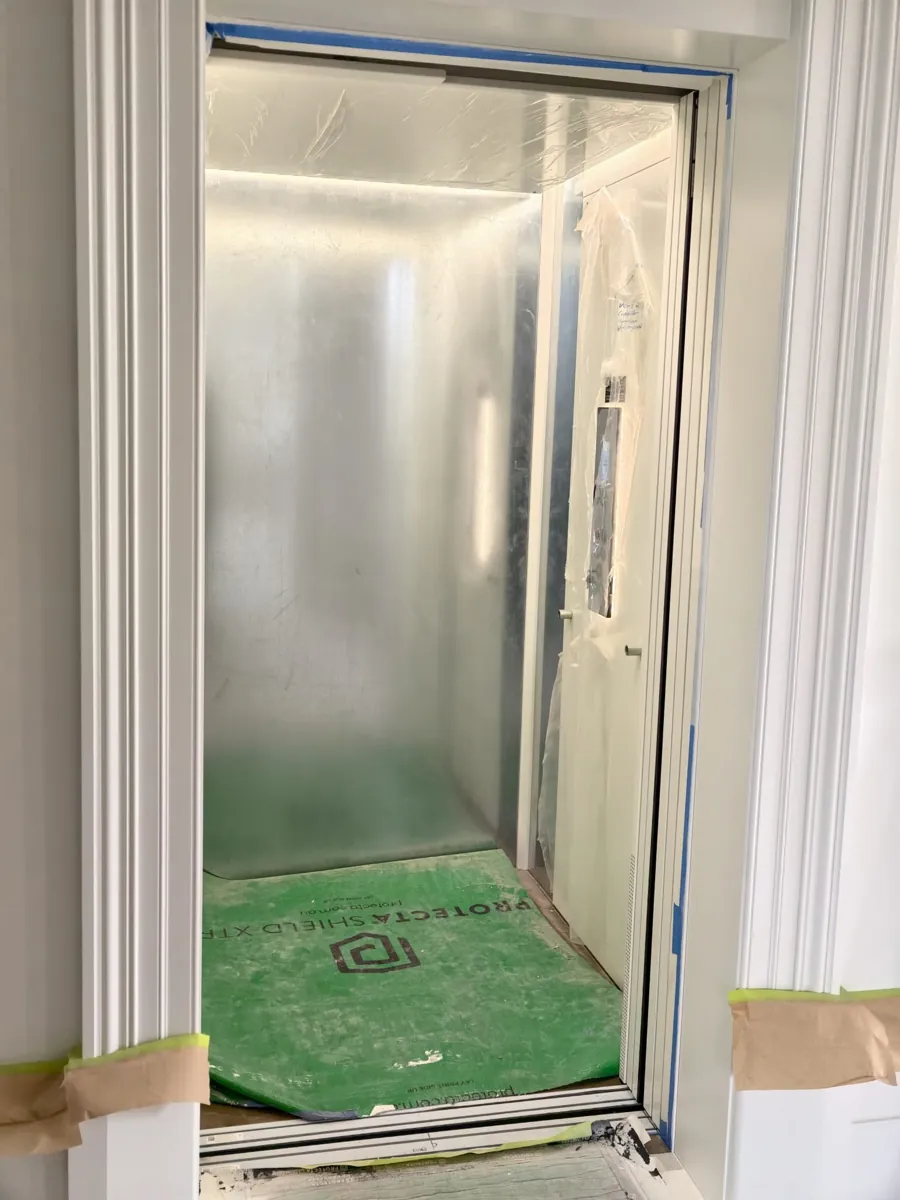 Elevator cabin during installation with protective covering and green floor mat in Blackburn